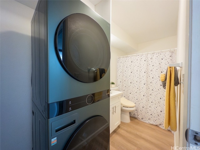 laundry area featuring stacked washing maching and dryer and light hardwood / wood-style floors