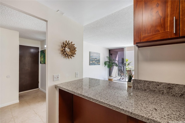 475 Atkinson Dr Unit 709, Honolulu, HI 96814 - kitchen featuring a textured ceiling, baseboards, brown cabinets, light stone counters, and light tile patterned floors