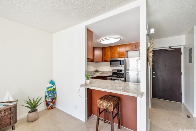 475 Atkinson Dr Unit 709, Honolulu, HI 96814 - kitchen with a breakfast bar area, a textured ceiling, appliances with stainless steel finishes, brown cabinetry, and light tile patterned floors