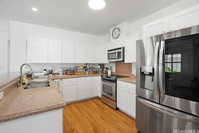 kitchen featuring sink, white cabinetry, light stone counters, light hardwood / wood-style flooring, and stainless steel appliances