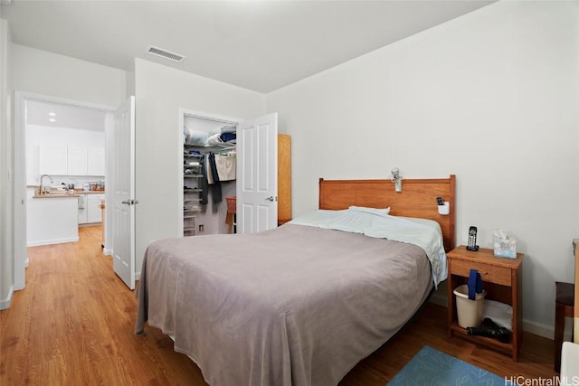 bedroom with sink, light hardwood / wood-style flooring, and a closet