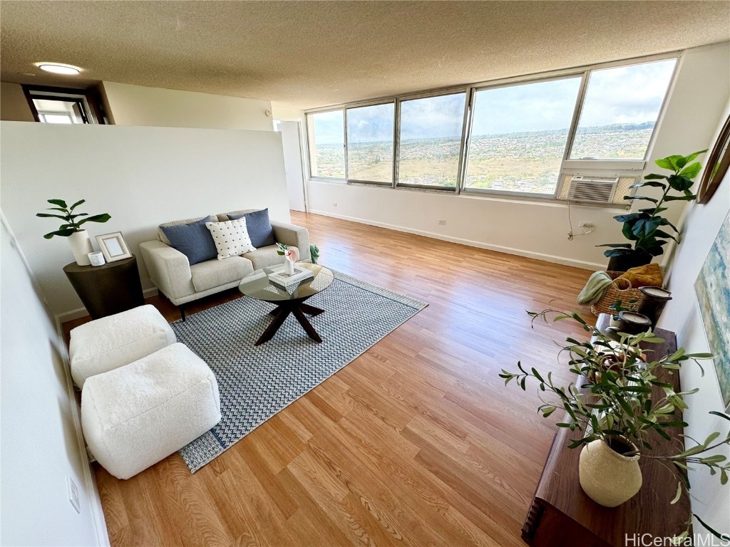 living room with a wealth of natural light, a textured ceiling, cooling unit, and light hardwood / wood-style flooring