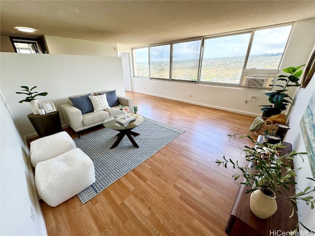 living room with a wealth of natural light, a textured ceiling, cooling unit, and light hardwood / wood-style flooring