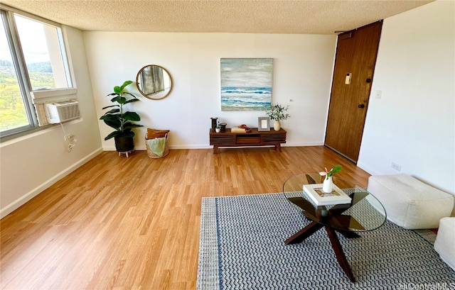 sitting room featuring light hardwood / wood-style floors, a textured ceiling, and cooling unit