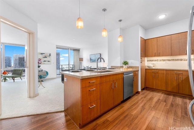 kitchen featuring sink, stainless steel dishwasher, kitchen peninsula, pendant lighting, and light hardwood / wood-style floors