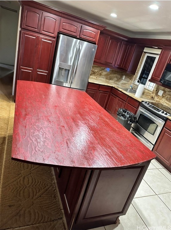 kitchen with appliances with stainless steel finishes, tasteful backsplash, and light tile patterned floors