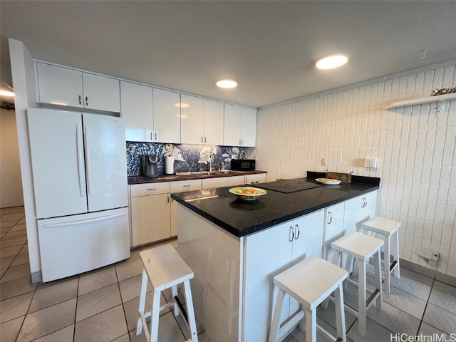 kitchen with white cabinetry, sink, a breakfast bar, black appliances, and light tile patterned floors