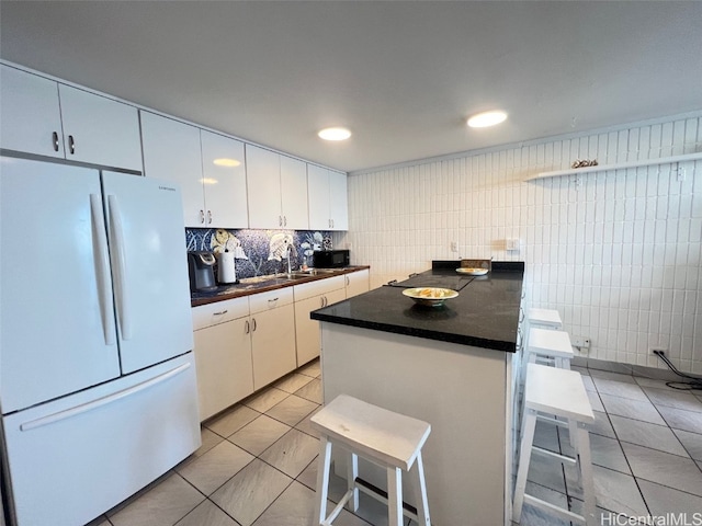 kitchen with a kitchen bar, white cabinets, and white refrigerator