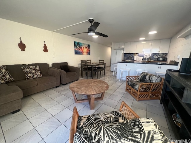 living room with light tile patterned floors, ceiling fan, and sink