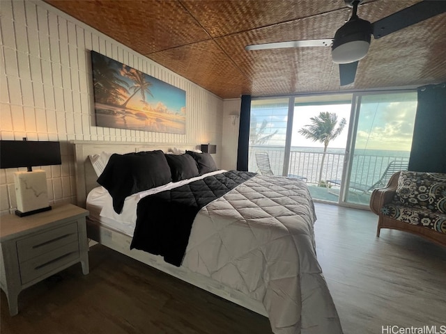 bedroom featuring hardwood / wood-style flooring, a water view, and access to outside