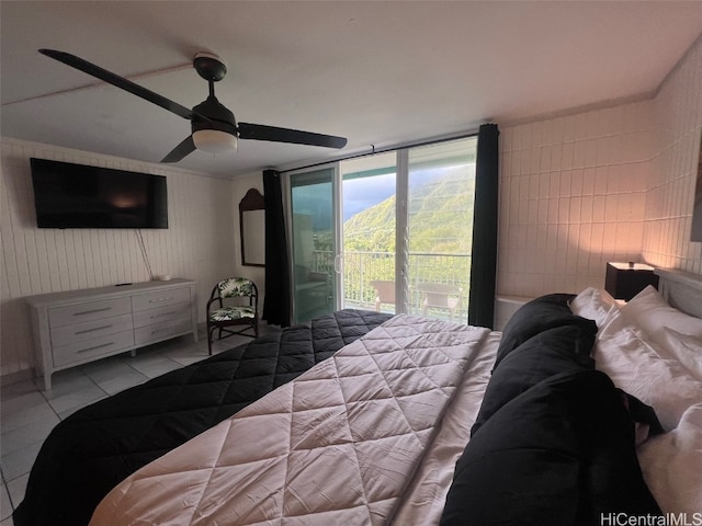 tiled bedroom with a mountain view, access to exterior, tile walls, and ceiling fan