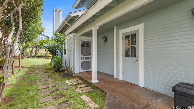 entrance to property with covered porch and a yard