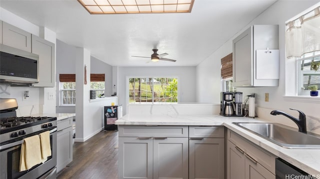 kitchen featuring dark wood-type flooring, gray cabinetry, stainless steel appliances, sink, and ceiling fan