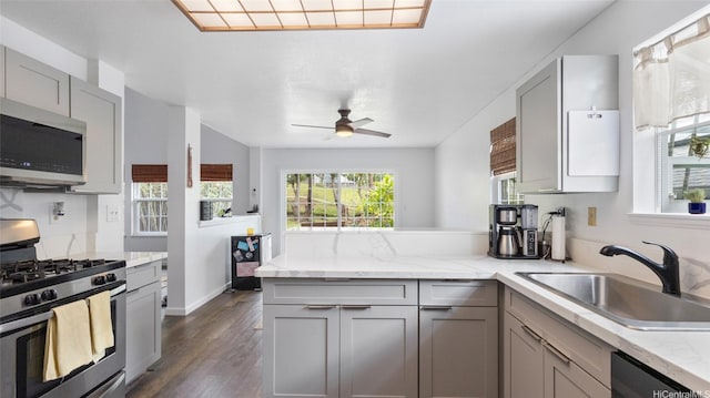 kitchen featuring a peninsula, ceiling fan, gray cabinets, a sink, and appliances with stainless steel finishes