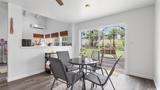 dining space featuring an AC wall unit, baseboards, and wood finished floors
