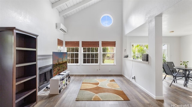 living room featuring beamed ceiling, a wall mounted air conditioner, hardwood / wood-style flooring, and high vaulted ceiling