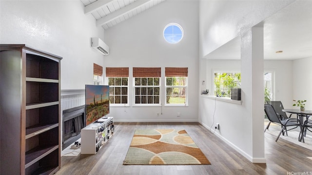 living room featuring baseboards, a wall unit AC, wood finished floors, and high vaulted ceiling