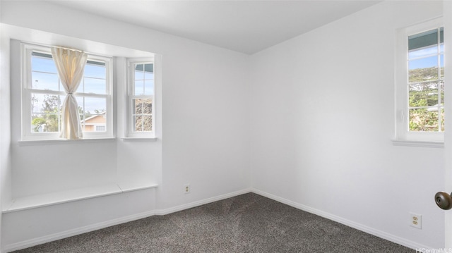 unfurnished room with baseboards, a healthy amount of sunlight, and dark carpet