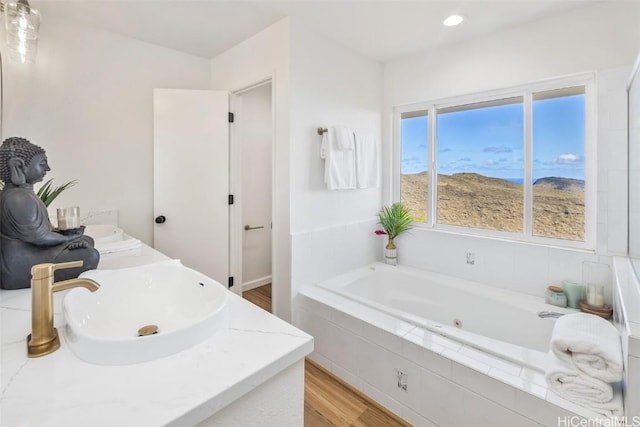 bathroom with tiled bath, vanity, and hardwood / wood-style flooring