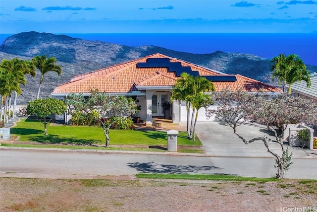 mediterranean / spanish home featuring a mountain view, a garage, and a front lawn