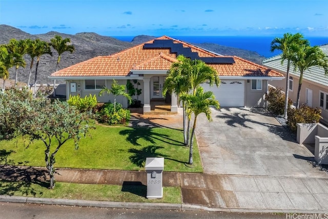 mediterranean / spanish-style house with solar panels, a mountain view, a front lawn, and a garage