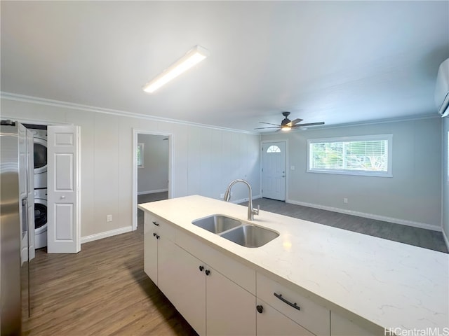 kitchen with crown molding, sink, dark hardwood / wood-style flooring, white cabinets, and stacked washer / drying machine