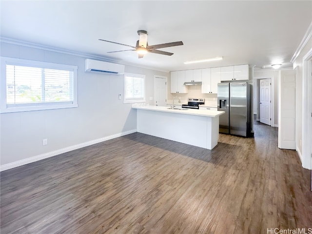 kitchen with a healthy amount of sunlight, appliances with stainless steel finishes, a wall unit AC, and white cabinets