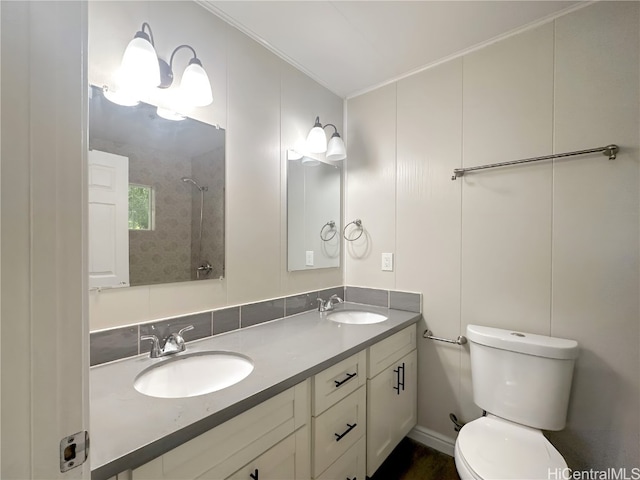 bathroom featuring vanity, toilet, crown molding, and tiled shower