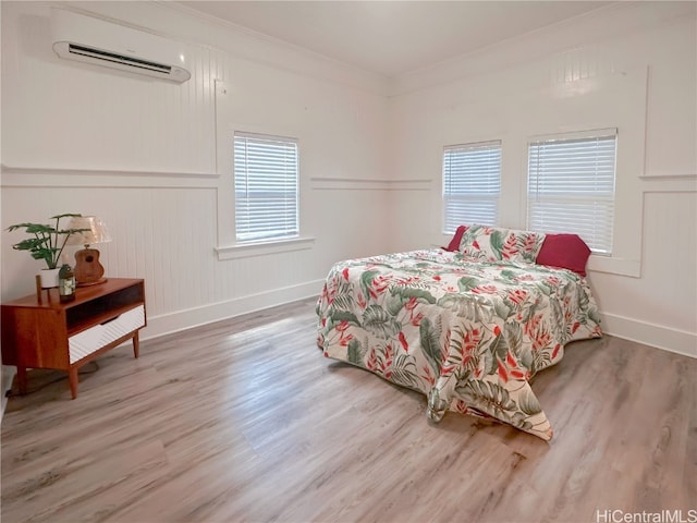 bedroom featuring a wall mounted AC, ornamental molding, and hardwood / wood-style floors