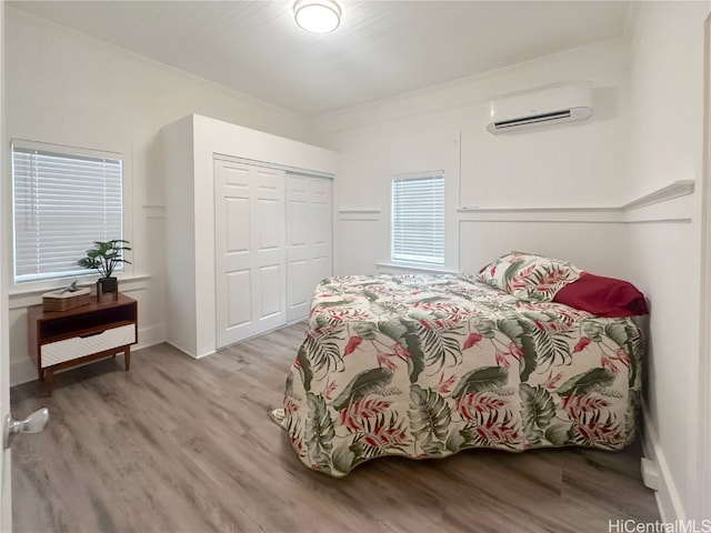 bedroom with a closet, light wood-type flooring, crown molding, and a wall mounted air conditioner