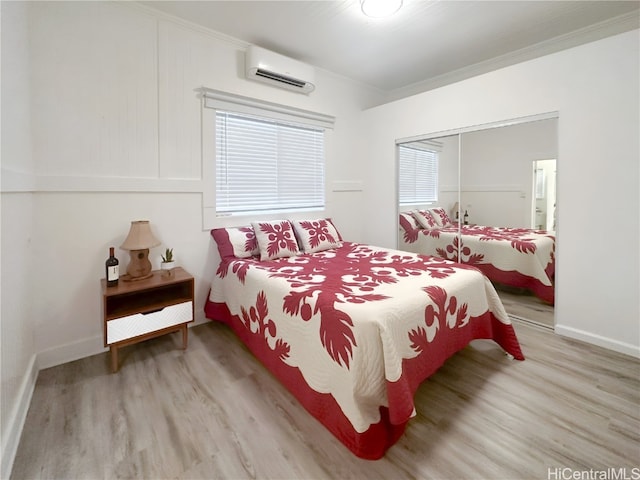 bedroom with a closet, crown molding, a wall mounted AC, and light hardwood / wood-style flooring