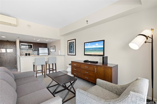 living room featuring rail lighting, sink, and a wall unit AC