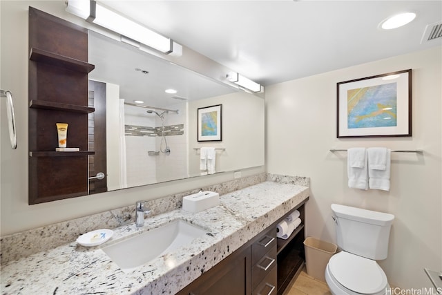 bathroom with vanity, tiled shower, toilet, and tile patterned flooring