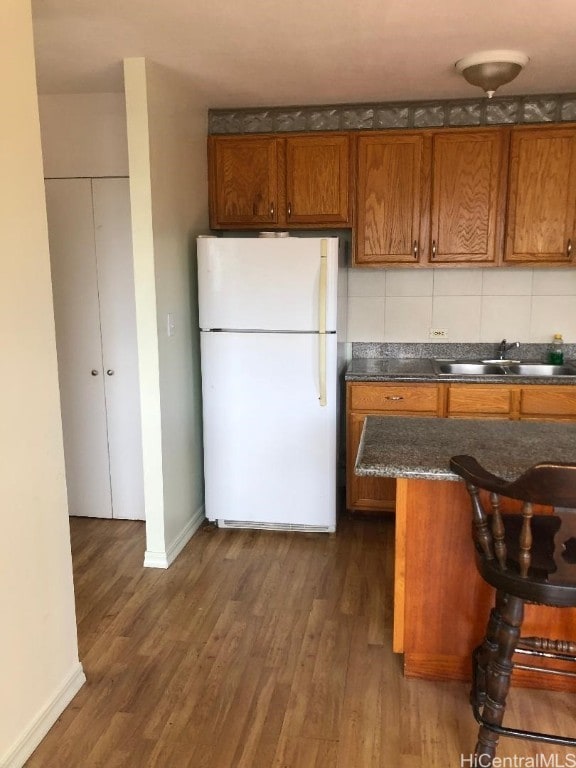 kitchen with decorative backsplash, white refrigerator, dark wood-type flooring, and sink