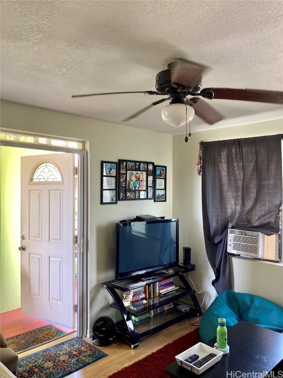 living room featuring hardwood / wood-style floors, ceiling fan, and a textured ceiling