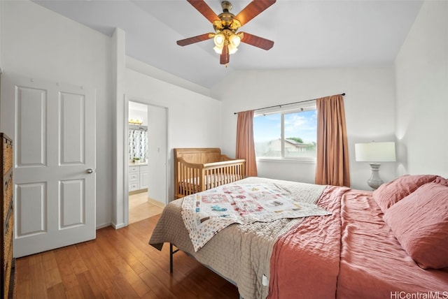 bedroom featuring light wood-type flooring, ensuite bath, ceiling fan, and lofted ceiling