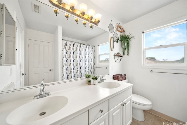 bathroom featuring tile patterned floors, a wealth of natural light, vanity, and toilet