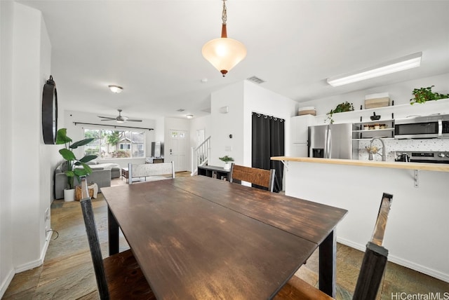 dining area with ceiling fan, dark wood-type flooring, and sink