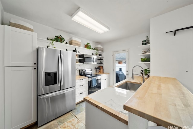 kitchen with white cabinets, kitchen peninsula, sink, and appliances with stainless steel finishes