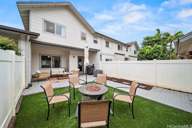 back of house featuring a yard, a patio, an outdoor living space with a fire pit, and central air condition unit