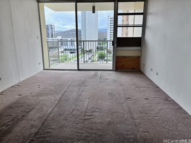 carpeted spare room featuring a mountain view and floor to ceiling windows