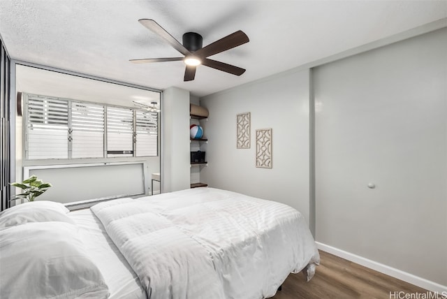 bedroom with ceiling fan, dark hardwood / wood-style flooring, and a textured ceiling