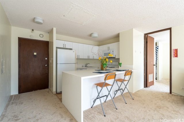 kitchen with a breakfast bar area, white cabinetry, light colored carpet, and white appliances