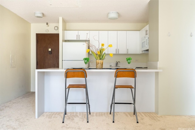 1925 Kalakaua Ave Unit 901, Honolulu, HI 96815 - kitchen with white appliances, carpet flooring, white cabinets, a peninsula, and a breakfast bar