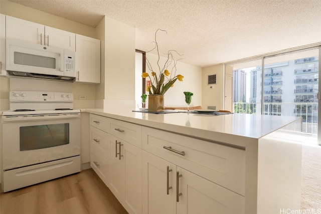 kitchen featuring light wood-style floors, white appliances, light countertops, and a peninsula