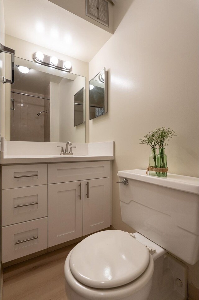 1925 Kalakaua Ave Unit 901, Honolulu, HI 96815 - bathroom featuring vanity, toilet, wood finished floors, and a tile shower