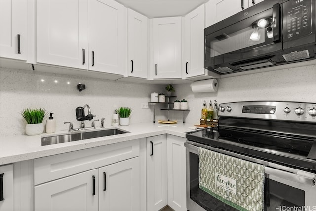 kitchen with light stone countertops, backsplash, stainless steel range with electric stovetop, sink, and white cabinets