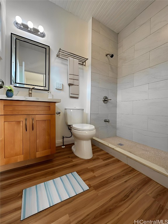 bathroom featuring toilet, hardwood / wood-style floors, vanity, and tiled shower