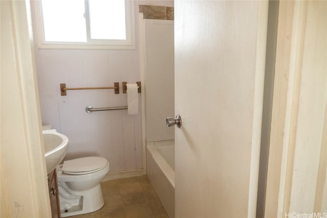 bathroom with toilet, a tub to relax in, and tile patterned floors