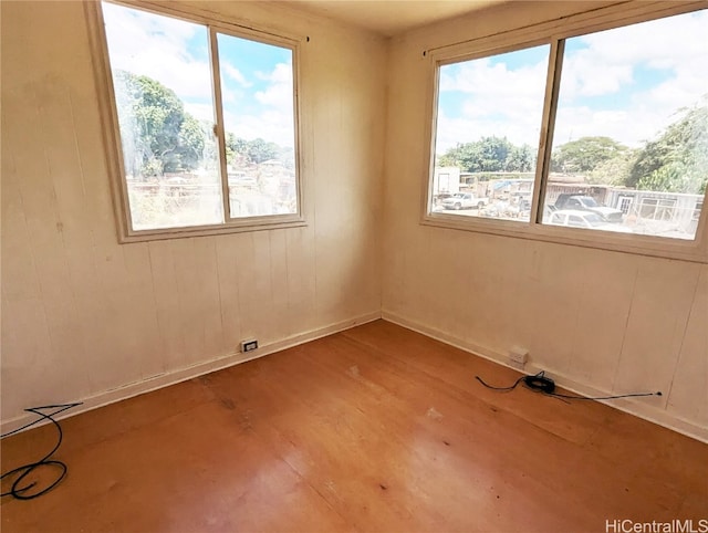 empty room featuring hardwood / wood-style floors, wooden walls, and plenty of natural light